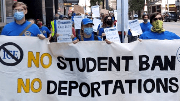 People holding a "No student ban, no deportations" sign