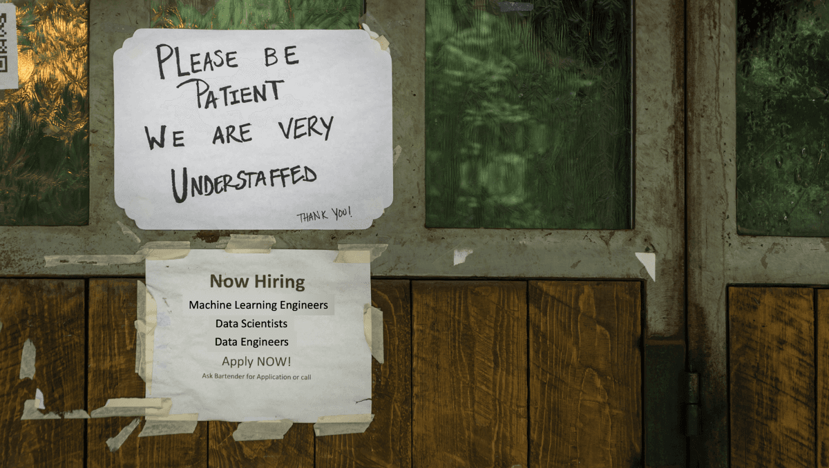 One sign with a message about being understaffed over a hiring sign for different engineering roles